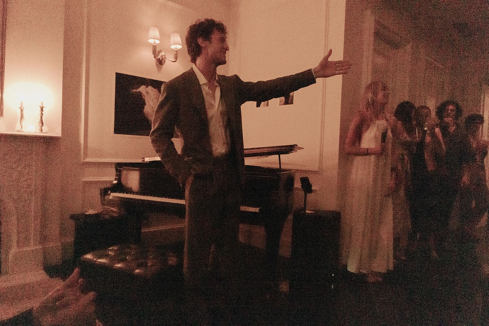 A pianist taking a bow by candlelight after a salon performance